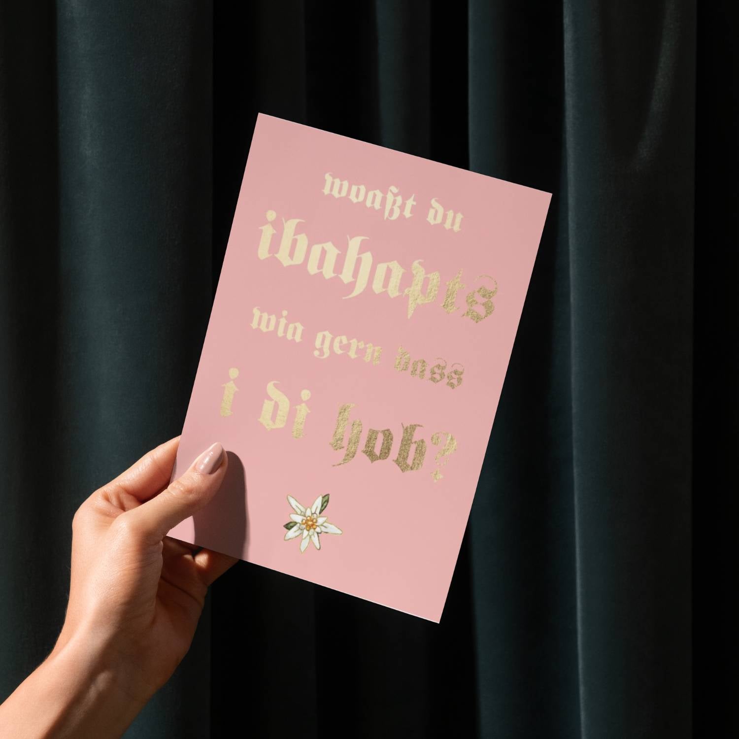 Glückwunschkarte wia gern i di hob, rosa mit goldenem Text, Edelweiß und Hand auf dunklem Hintergrund.