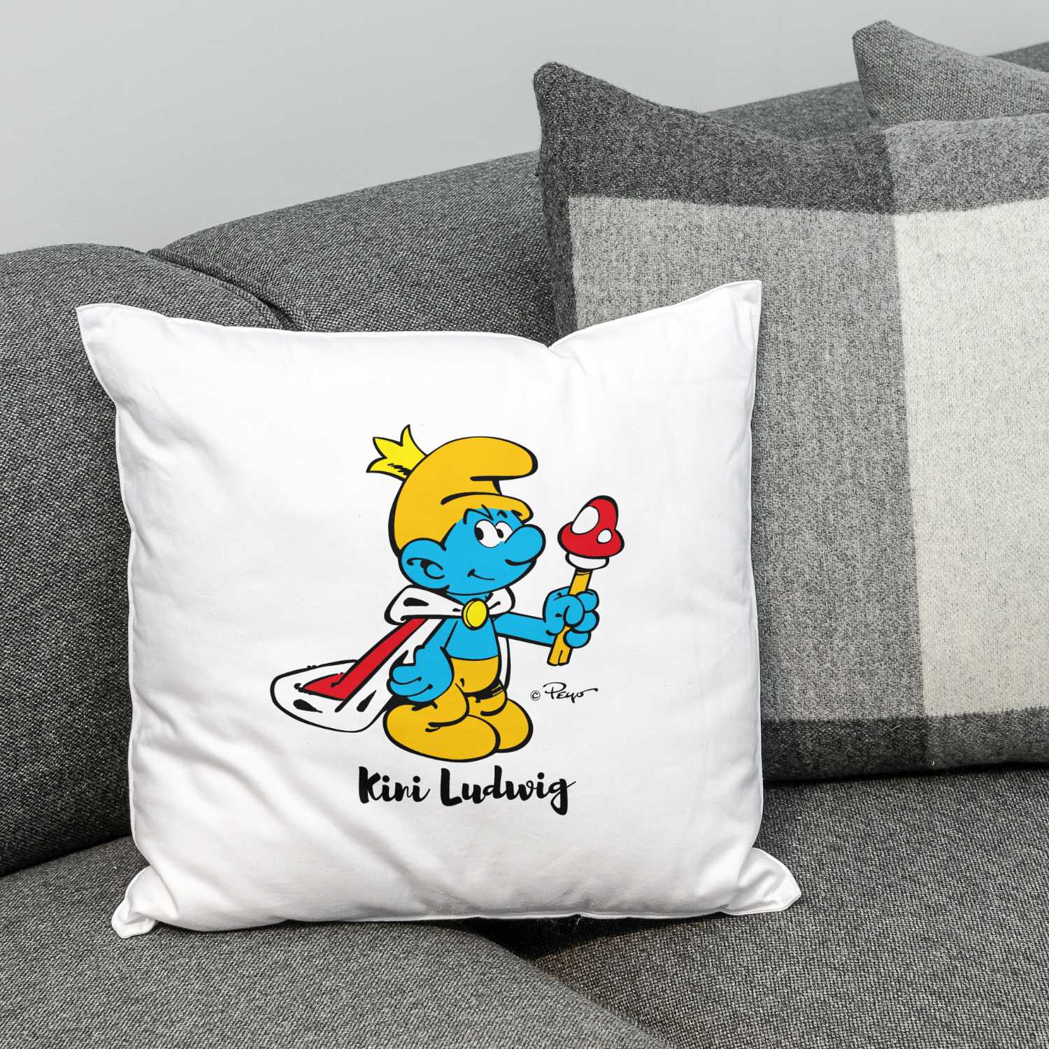 ®Die Schlümpfe Kini Kuschelkissen personalisiert mit Schlumpf im Königsoutfit und Pilz auf Sofa, gemütliches Geschenk