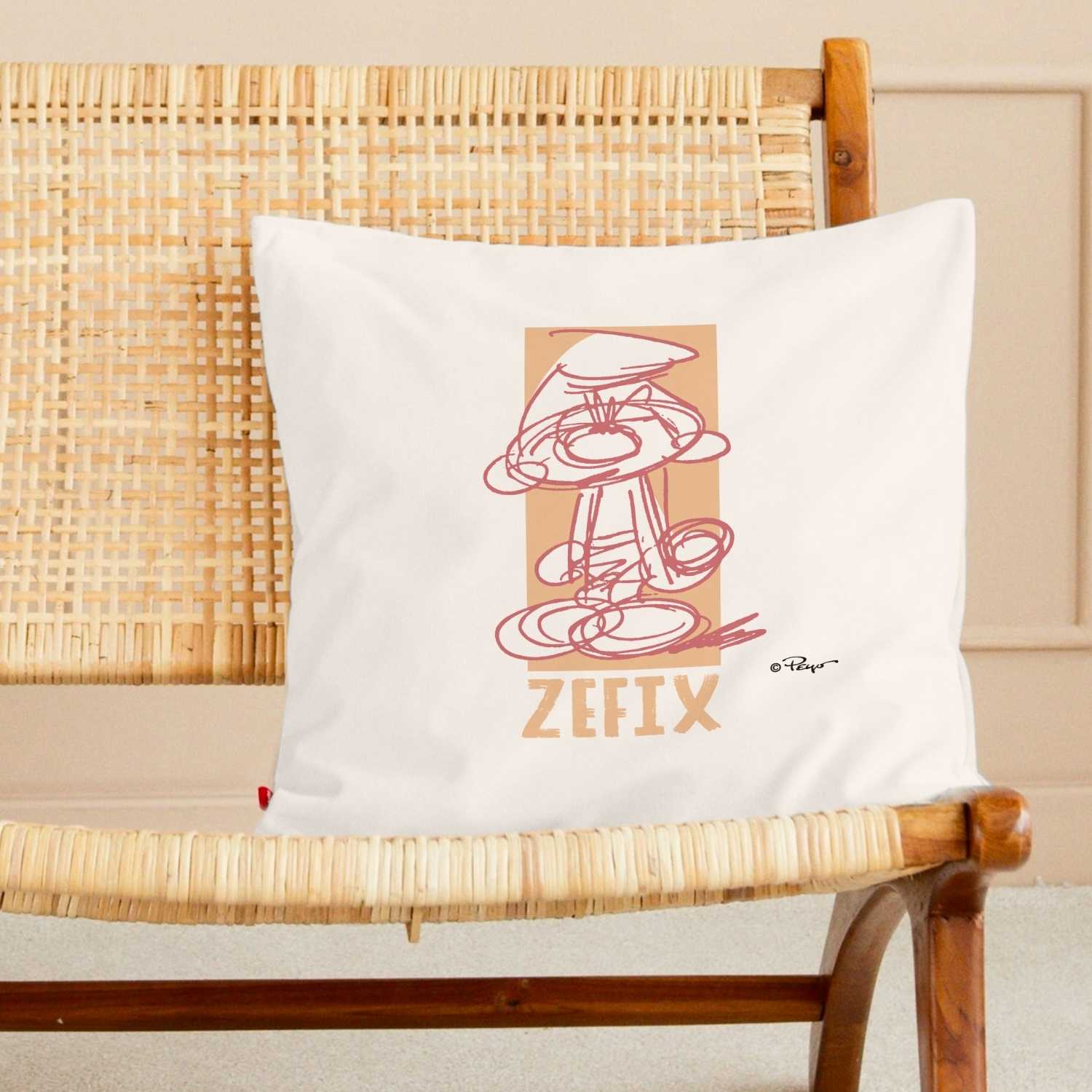 ®Die Schlümpfe Zefix Kuschelkissen auf einem Holzstuhl mit Rattan-Geflecht, mit abstraktem Schlumpf-Motiv.