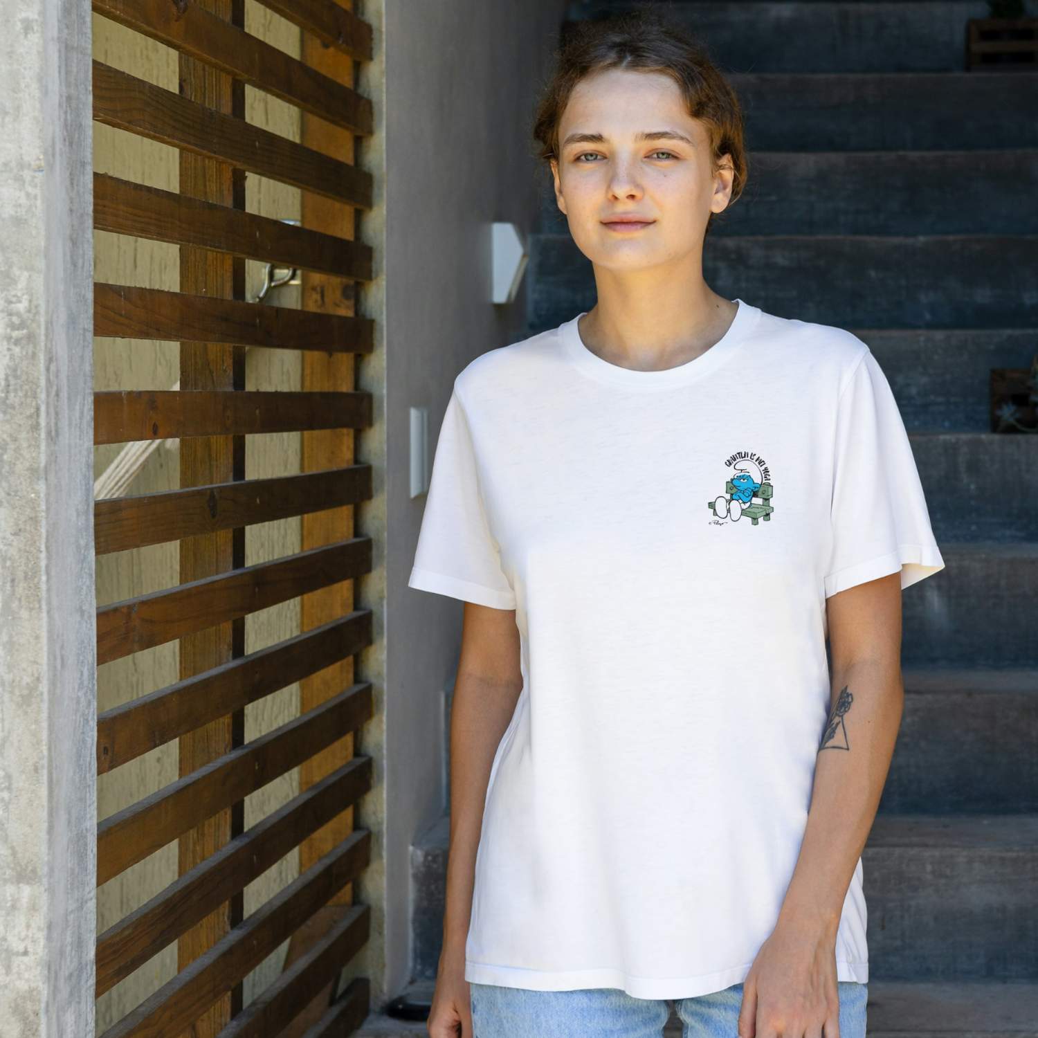 Damen T-Shirt Die Schlümpfe Grantln is mei Yoga, Model trägt weißes Oberteil mit bedrucktem Schlumpf-Motiv