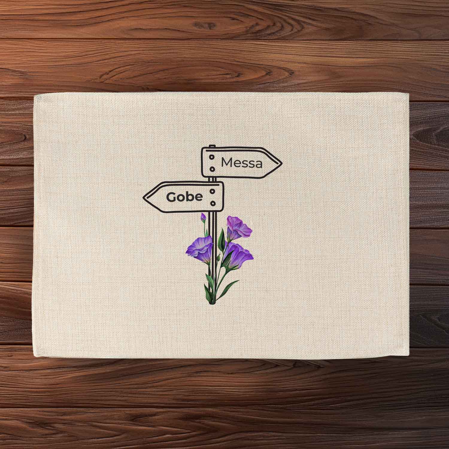 Tischset Wegweiser beige mit schwarzem Schild und lila Blumen auf Holztisch, Text "Gobe" und "Messa