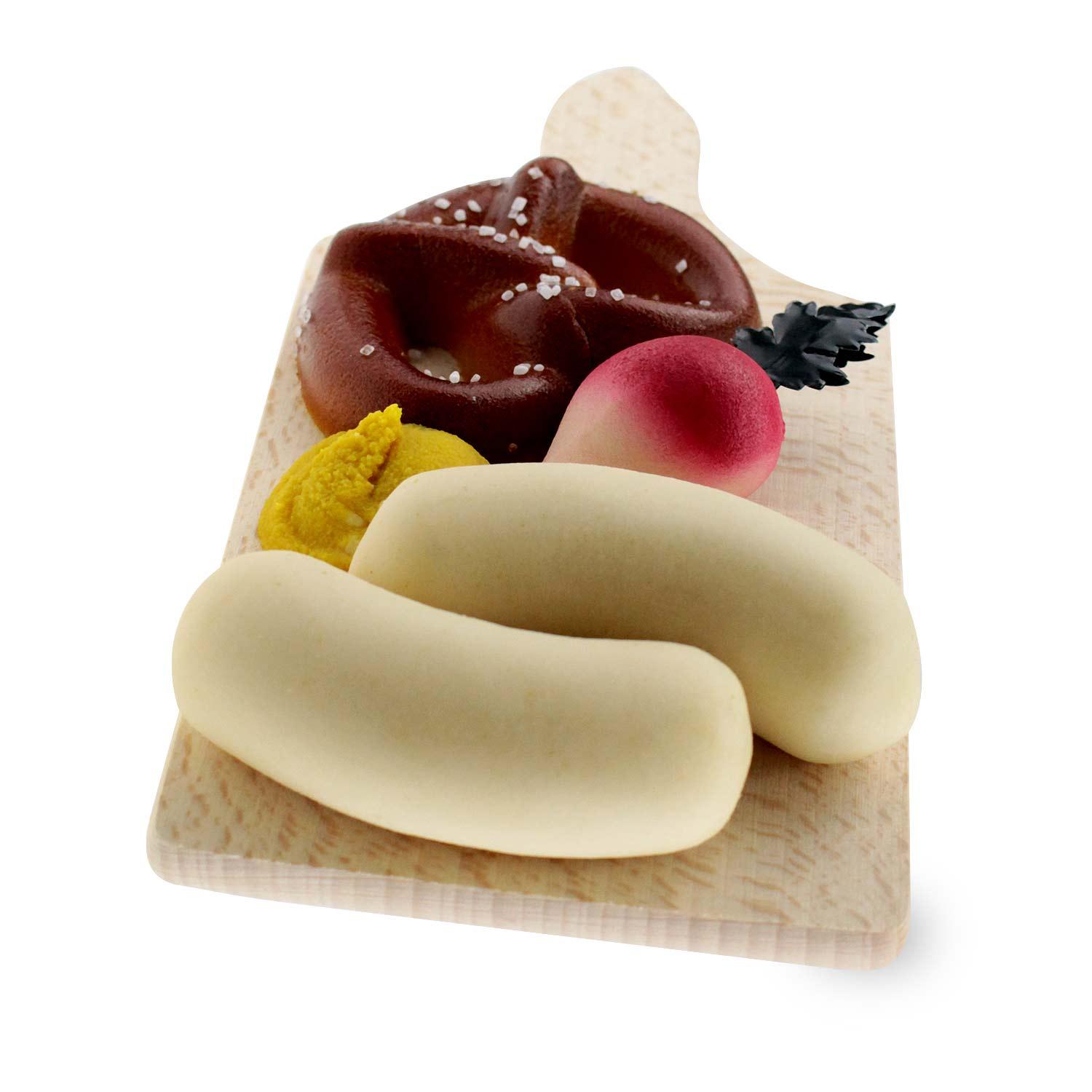 Miniatur-Weißwürste mit Brezel, Senf und Radi auf einem Holzbrettchen als bayerisches Souvenir