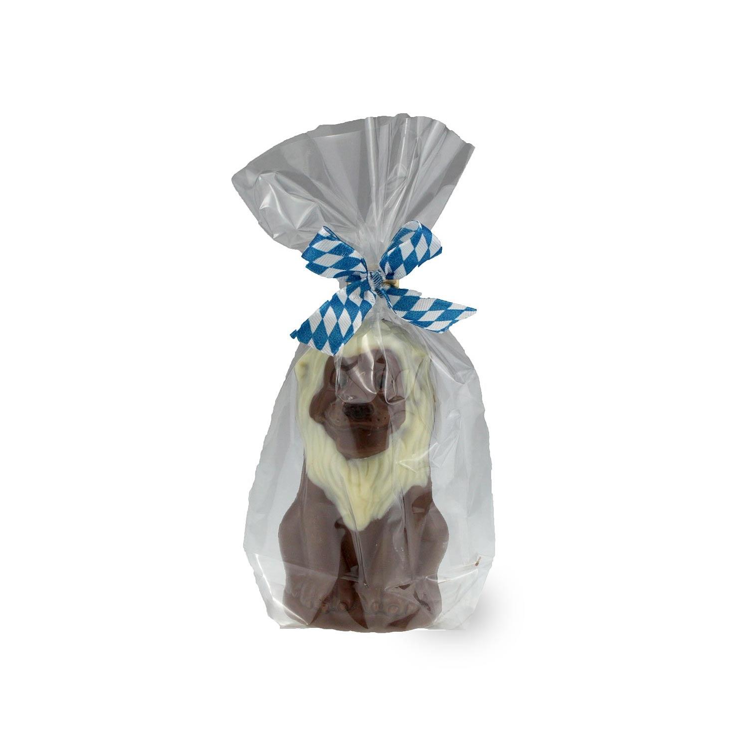 Bayrischer Schoko-Löwe aus Vollmilchschokolade mit weißer Schokolade Mähne, in Geschenkfolie mit blau-weißem Band.