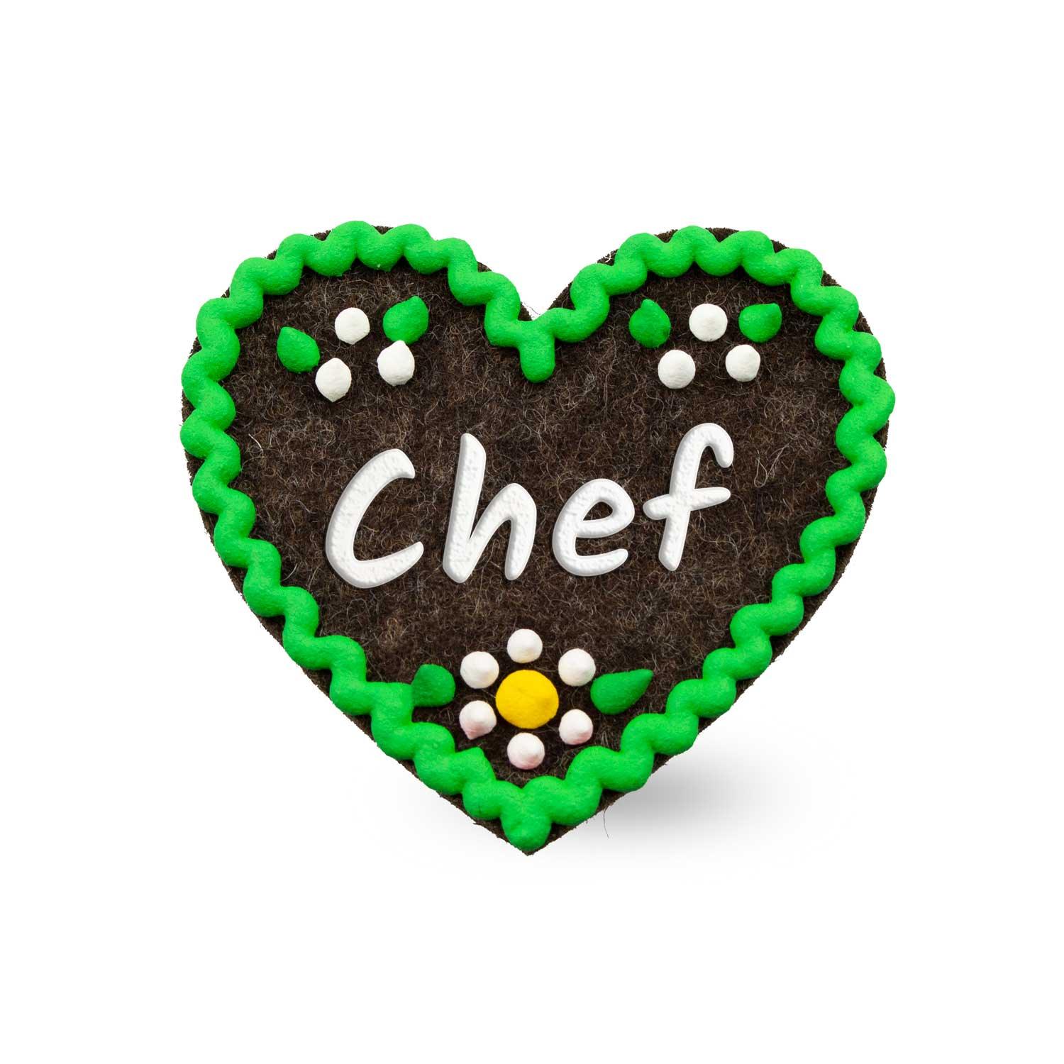 Brauner Filzherz-Anstecker "Chef" mit grünem Rand, weißen Details und kleiner floraler Verzierung.