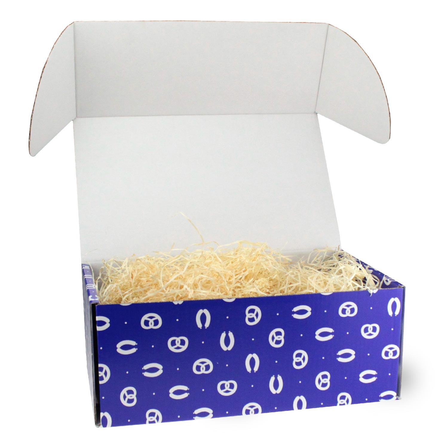 Geschenkbox Fias Lausdirndl geöffnet, blau-weißer Brezel-Druck, gefüllt mit Holzwolle für Geschenke.