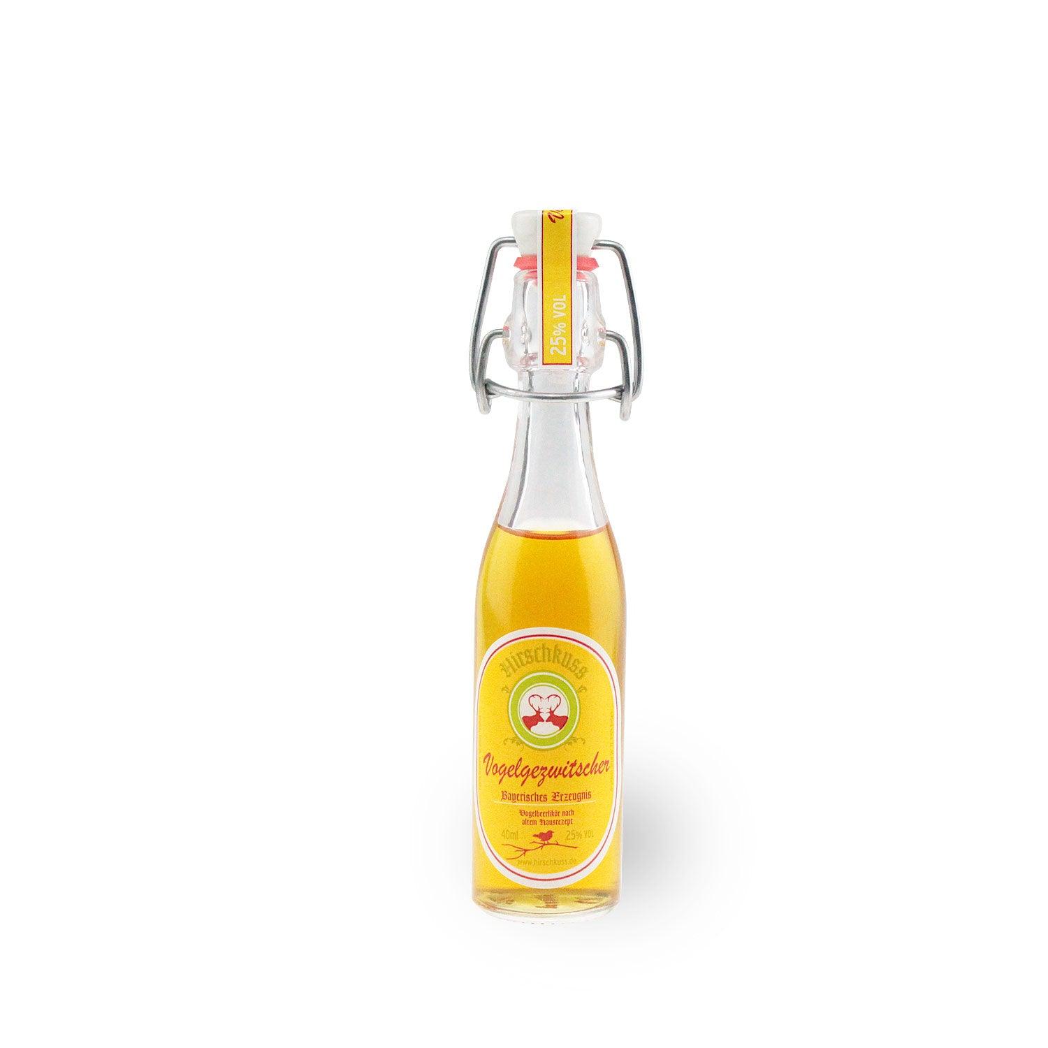 Klarer, bernsteinfarbener Vogelbeerlikör in Mini-Flasche mit rotem Etikett, Schriftzug „Vogelgezwitscher“, 25 % vol., 40 ml.