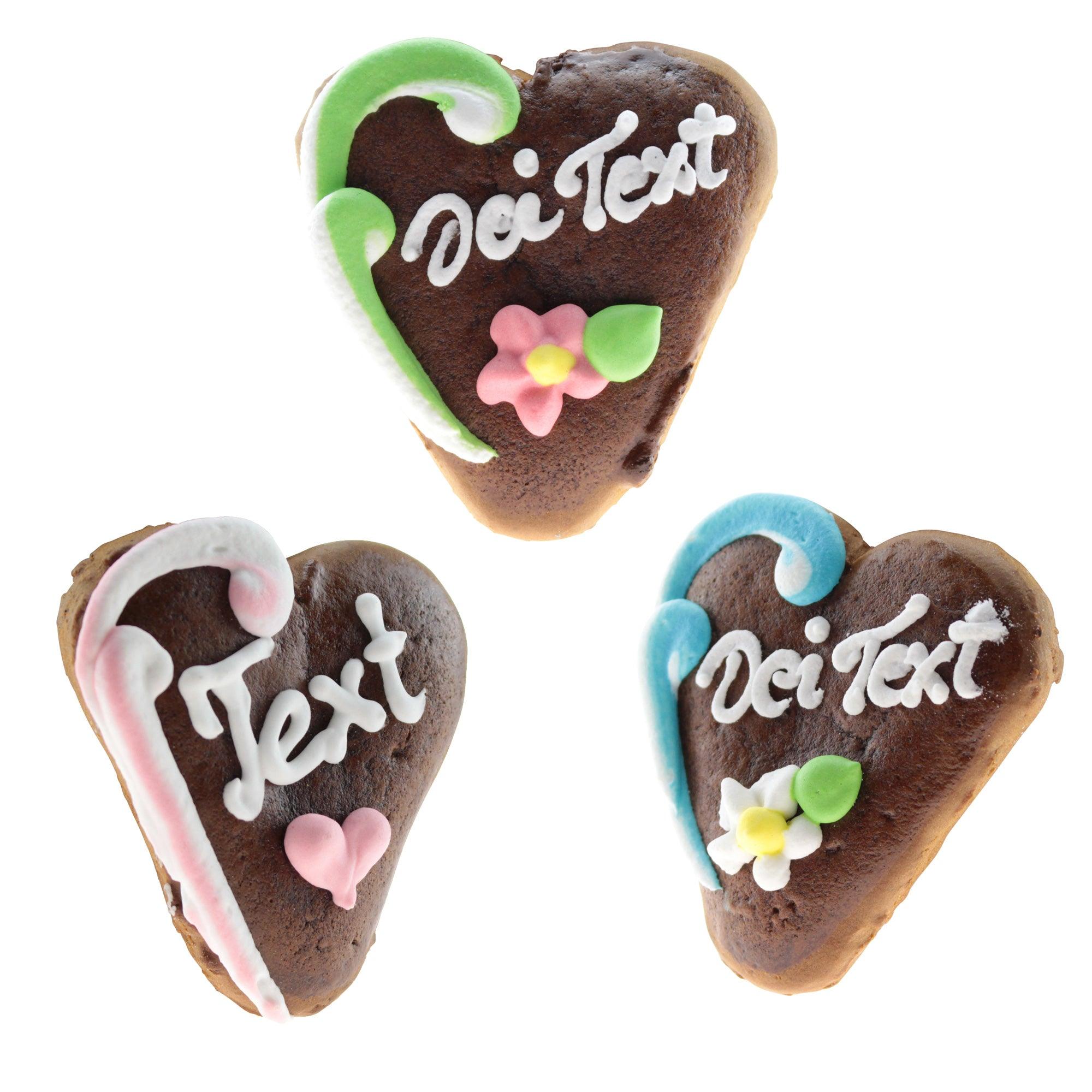 Drei herzförmige Lebkuchen, verziert mit Zuckerguss in verschiedenen Farben und den Schriften "Dei Text".