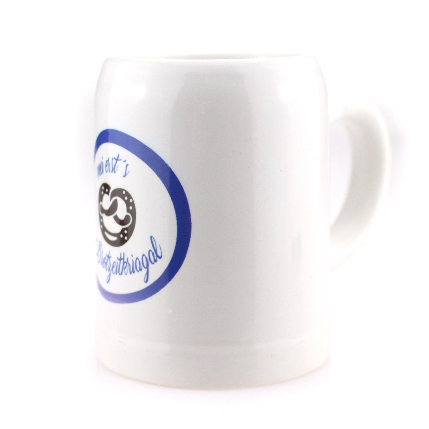 Weißer Keramik-Bierkrug mit blauem Aufdruck und Brezel-Motiv für bayerisches Bier.