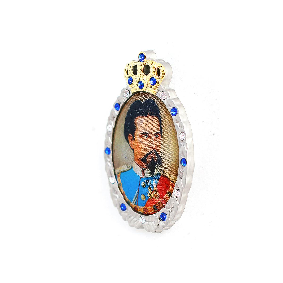 Ovale Anstecknadel mit Konterfei von Ludwig II., besetzt mit blauen und weißen Strasssteinen und goldener Krone.