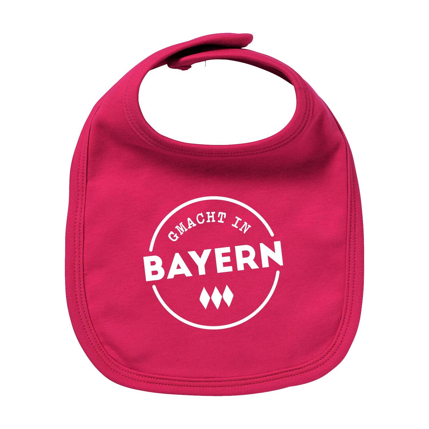 Rosa Baby-Lätzchen "Gmacht in Bayern" mit weißem Schriftzug und Rautenmuster, weiche Baumwolle.
