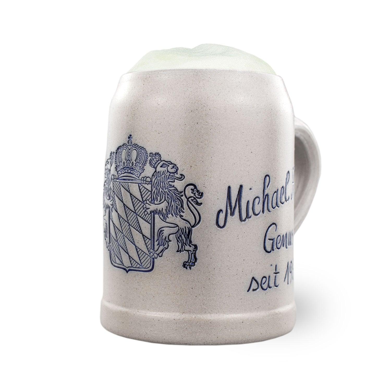 Grauer Keramik-Bierkrug mit blauem bayerischem Wappen, goldener Krone und personalisierter Aufschrift "Michael Genuss seit 19xx".