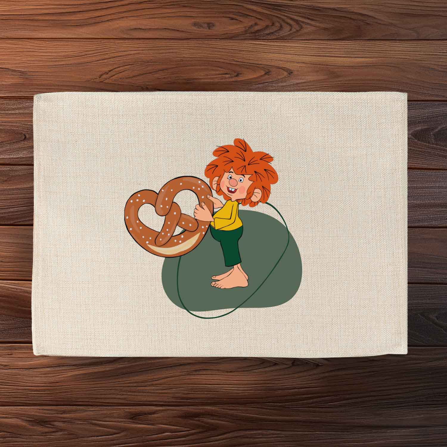 Abwaschbares Pumuckl Tischset mit Motiv des Kobolds, der eine große Brezel hält, auf hellem Stoff.