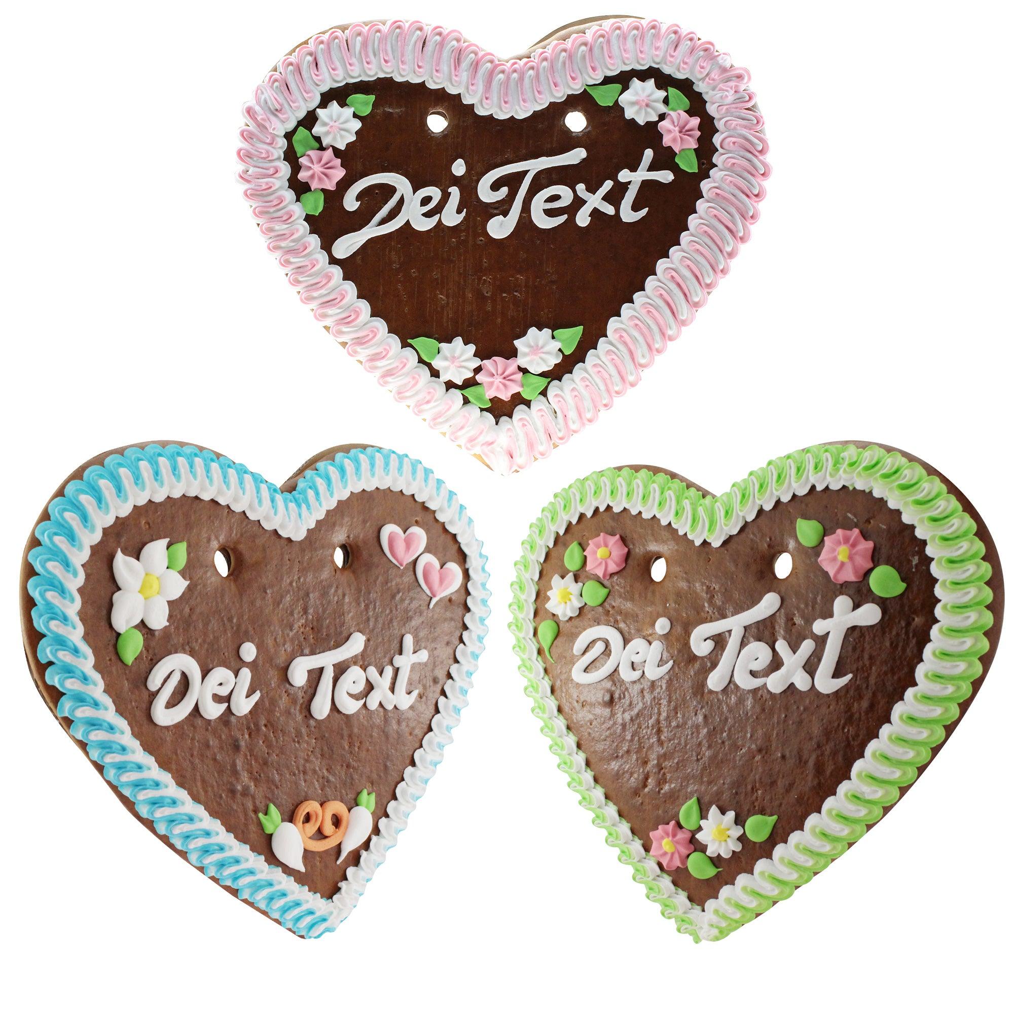 Drei bunte Lebkuchenherzen mit individueller Aufschrift "Dei Text", rosa, blau und grün verziert.