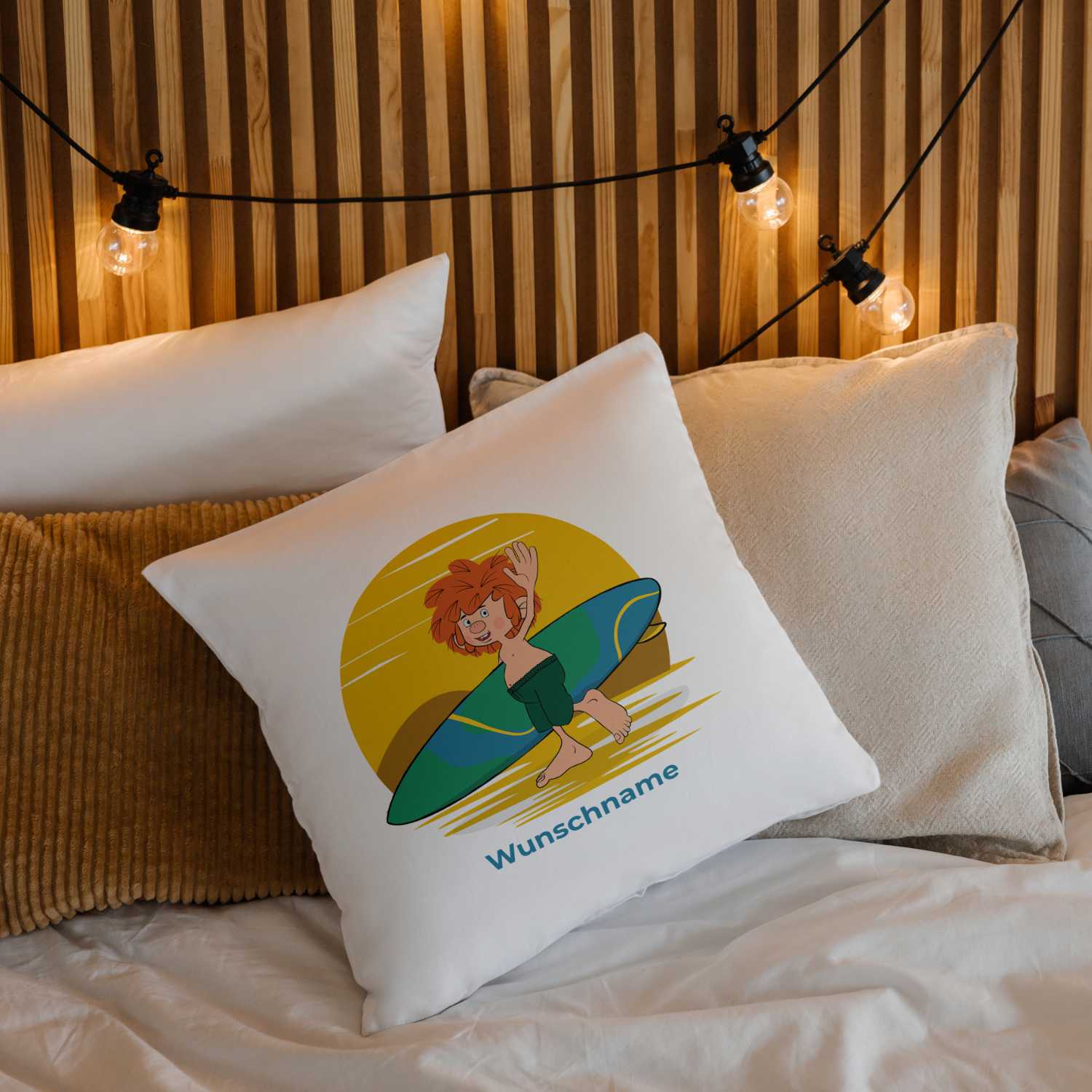 Pumuckl Kuschelkissen Surfer auf weißem Kissen mit Personalisierungsoption, liegt dekorativ auf einem Bett.