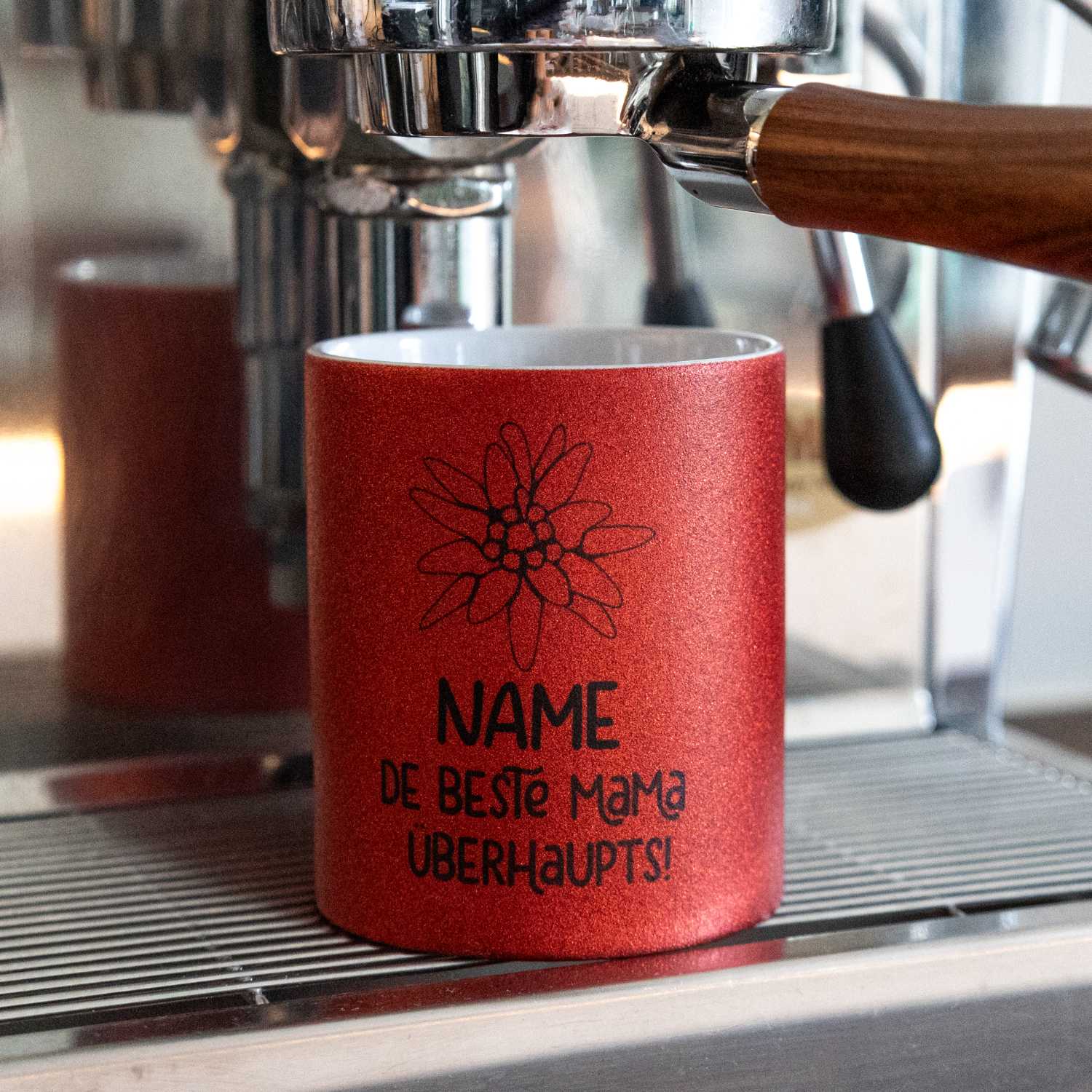 Rot glitzerndes Kaffee Haferl "De beste Mama überhaupts" personalisiert mit Edelweiss-Motiv in Siebträgermaschine