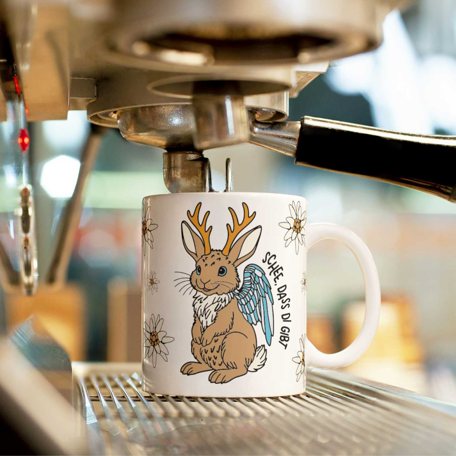 Kaffee Haferl Wolpertinger mit Hasenmotiv, Geweih, Flügeln und Edelweiß, unter Kaffeemaschine.