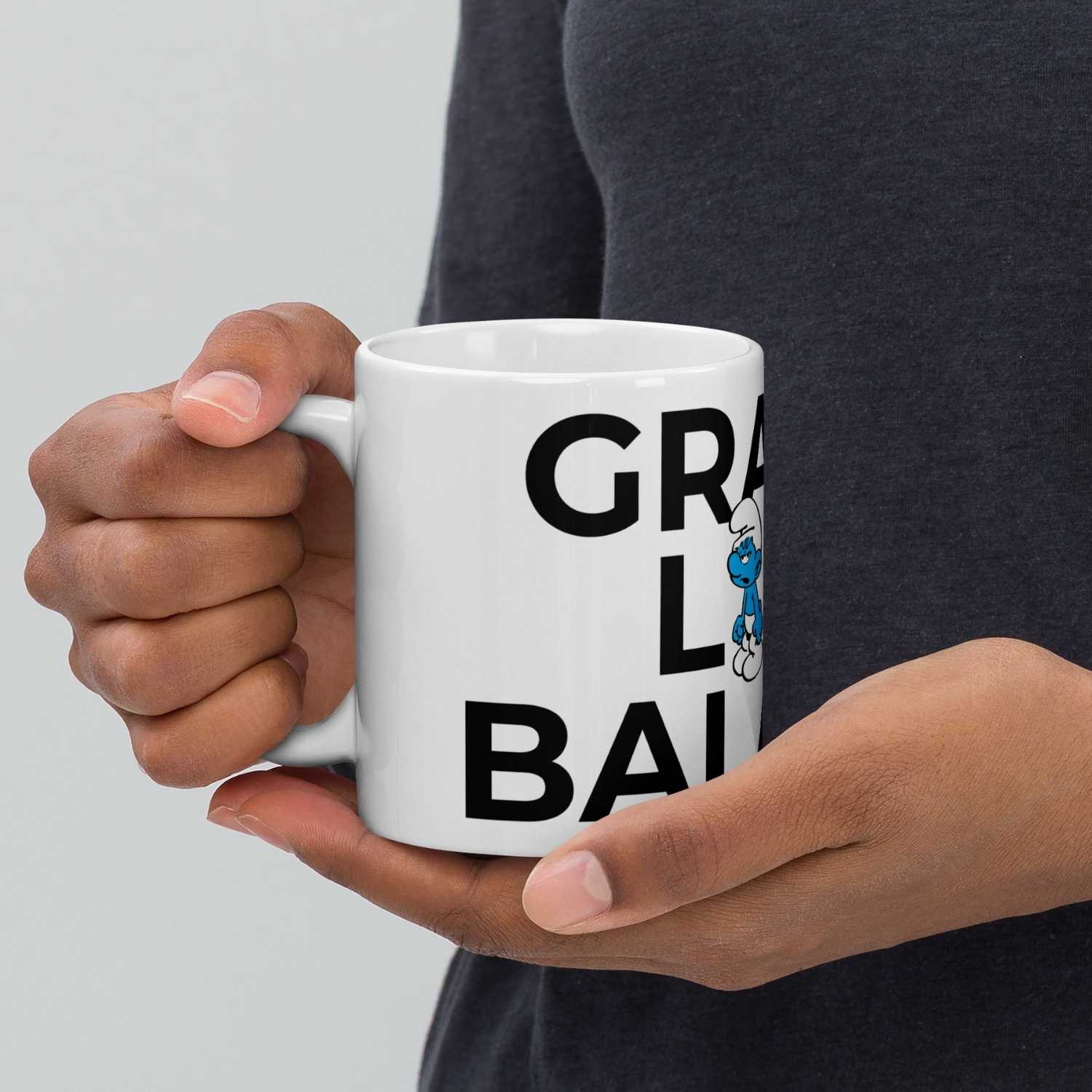 Weiße Schlümpfe Tasse Grantl life balance mit Grantelbart Comic Figur und großem Schriftzug, gehalten von einer Hand.