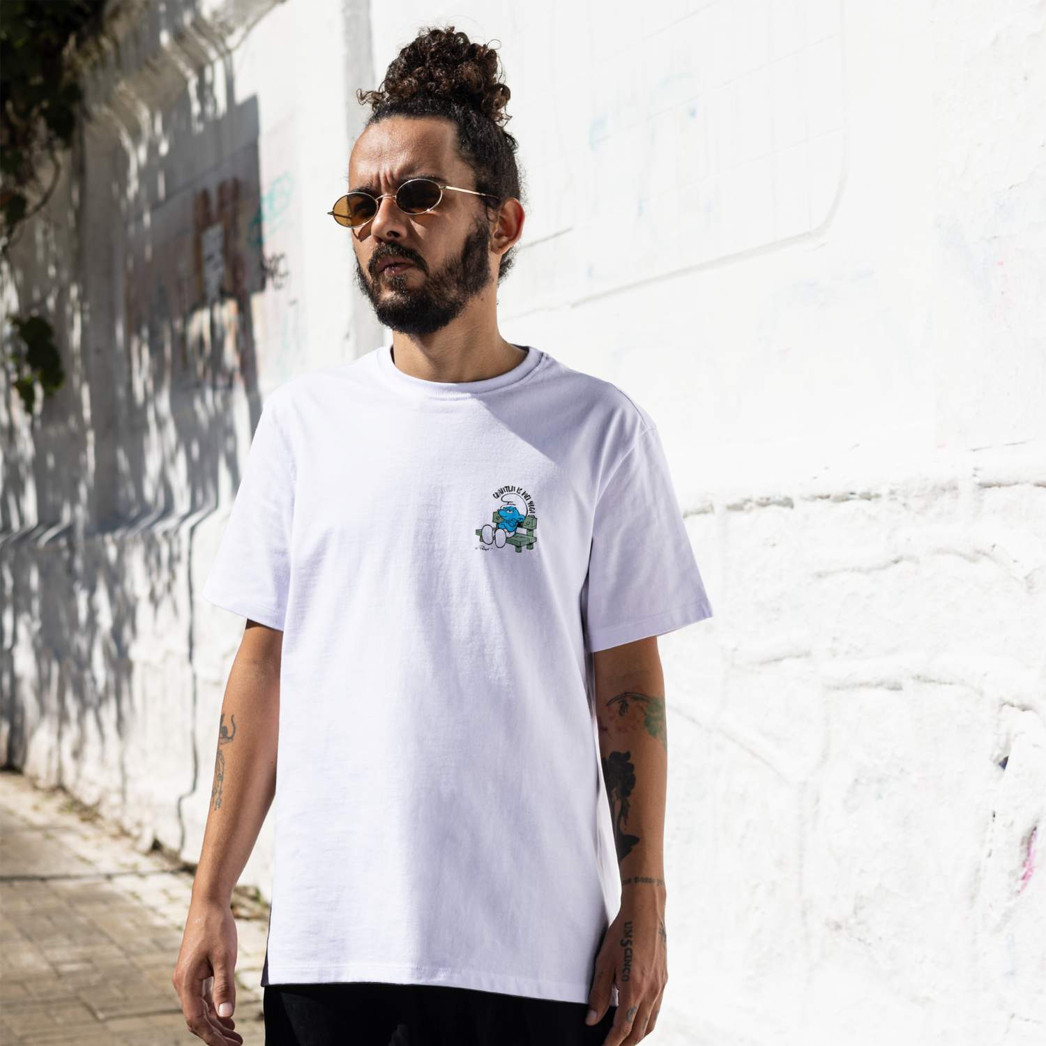 Mann mit Dutt trägt das weiße Schlümpfe Herren T-Shirt Grantln is mei Yoga mit Schlaubi Schlumpf-Print.