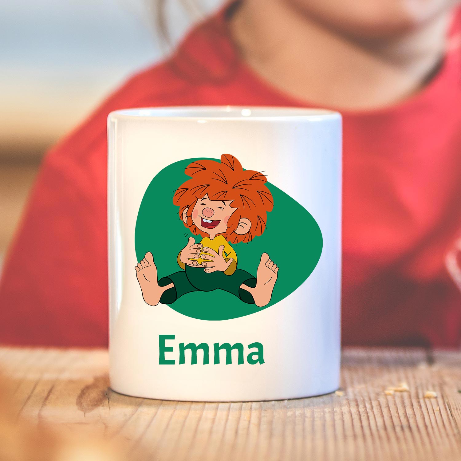Weiße ®Pumuckl Tasse mit lustiger Zeichnung und individuellem Namensdruck Emma auf Echtholzoberfläche.