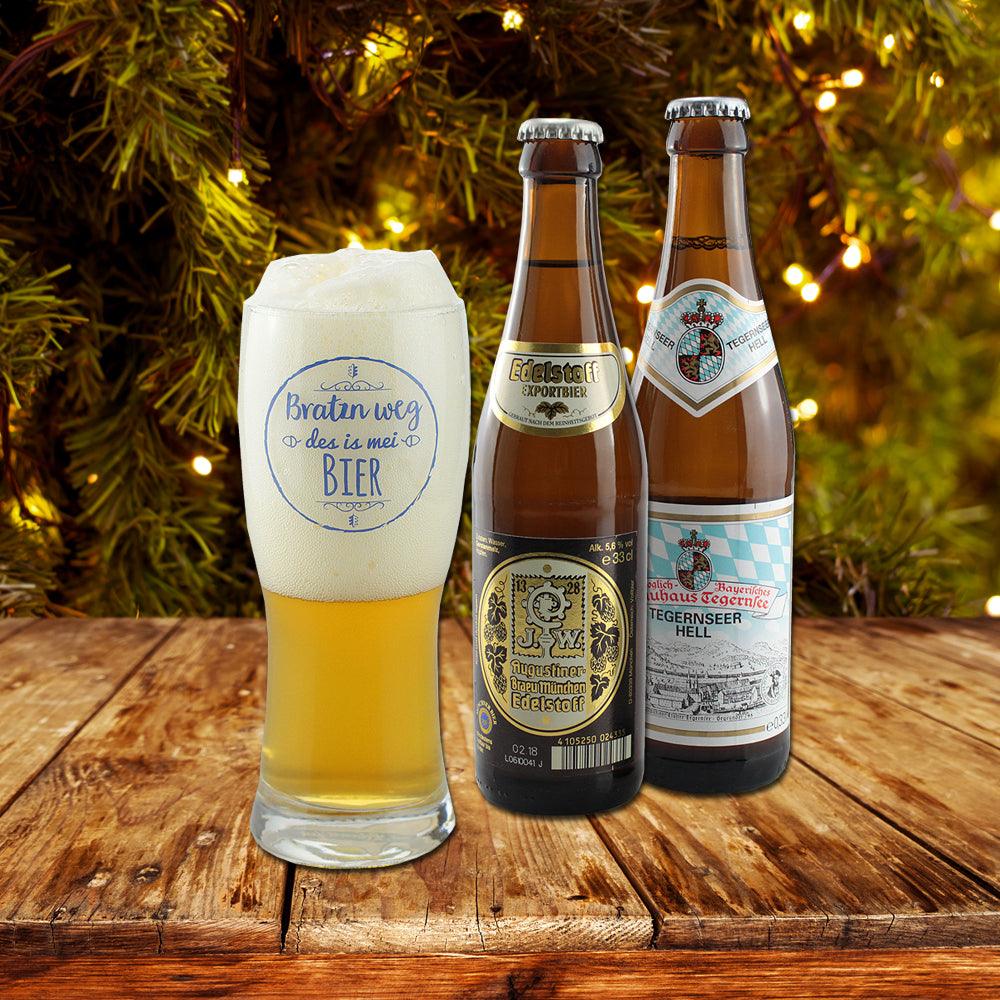 Gefülltes Bierglas mit bayerischem Spruch Braten weg des is mei Bier und zwei Flaschen Exportbier auf Holztisch