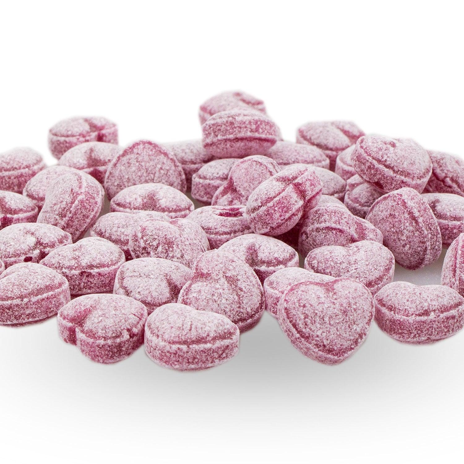 Boarische Herzal-Guadl: Ein Haufen herzförmiger, rosa Bonbons mit weißer Zuckerbeschichtung auf weißem Hintergrund.