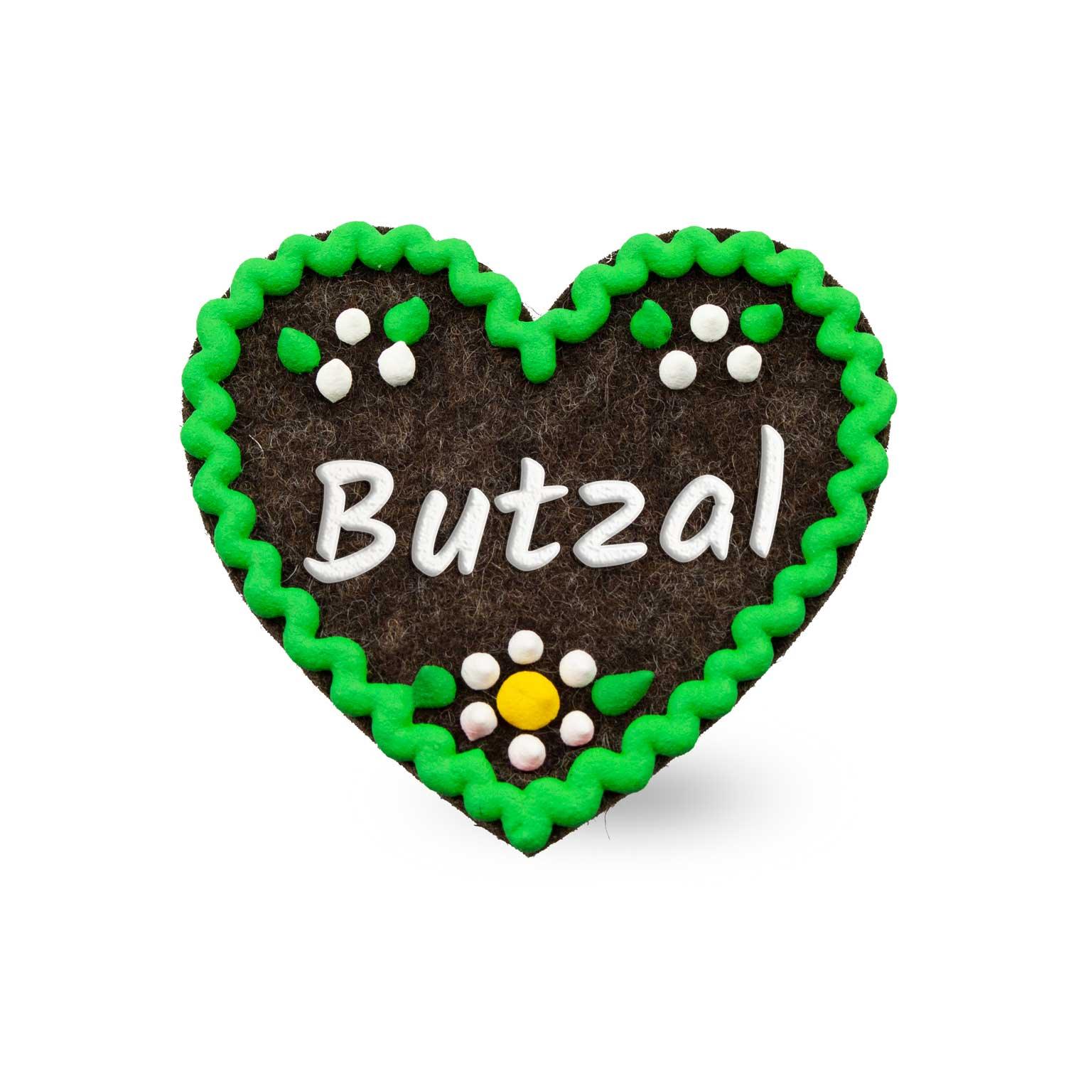 Brauner Filzherz-Anstecker Butzal mit grünem Rand, weißen Punkten und gelber Blume, traditionelles Trachtenaccessoire.