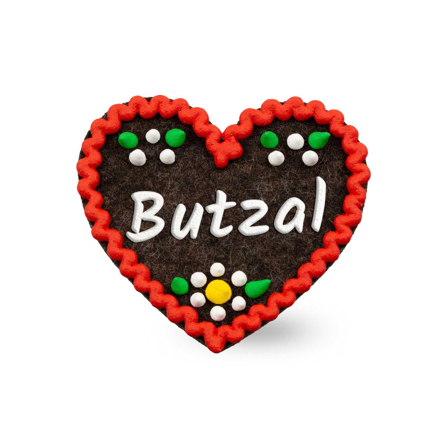 Brauner Filzherz-Anstecker Butzal mit rotem Rand, weißen Buchstaben und bunten Filzblumen.
