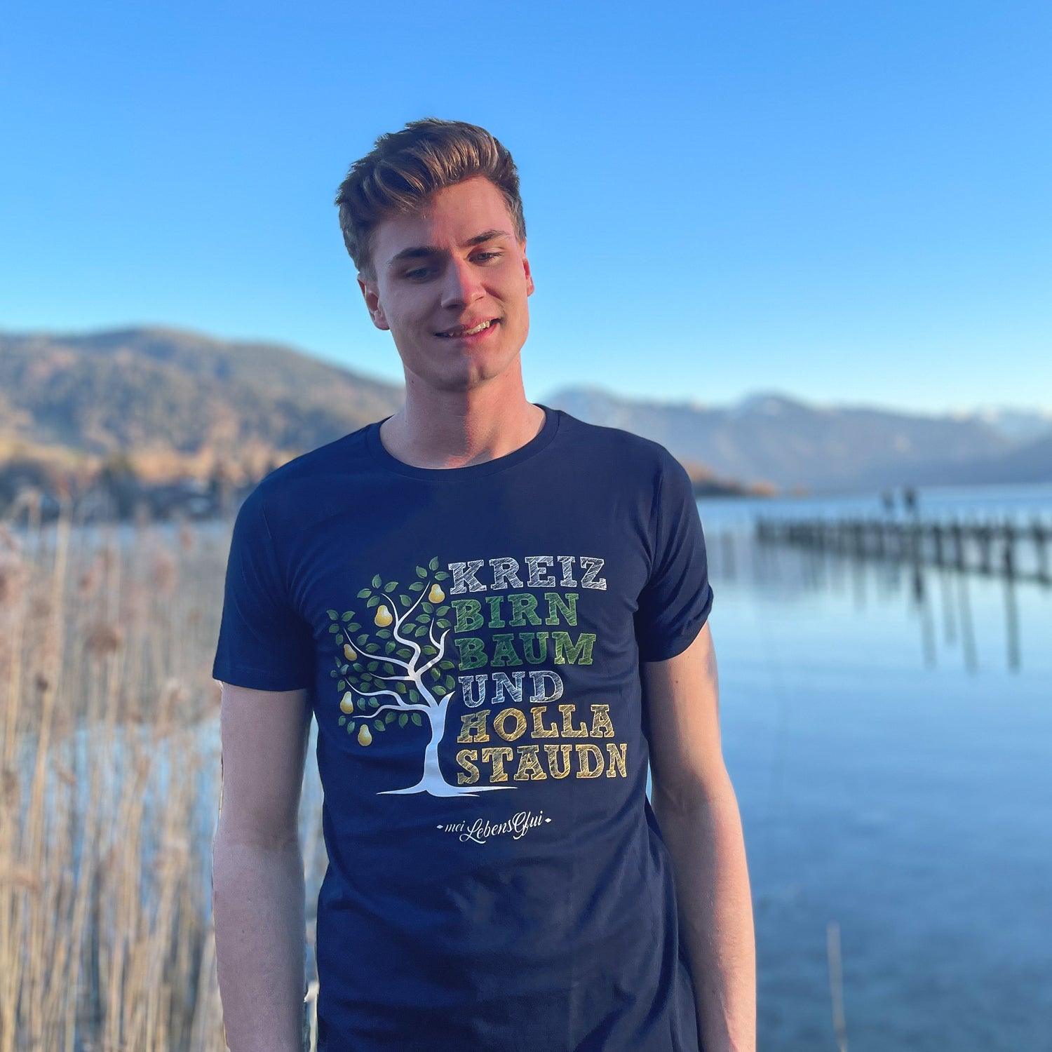 Junger Mann trägt navyblaues Herren T-Shirt "Kreizbirnbaum" mit Birnenbaum-Print am Seeufer.