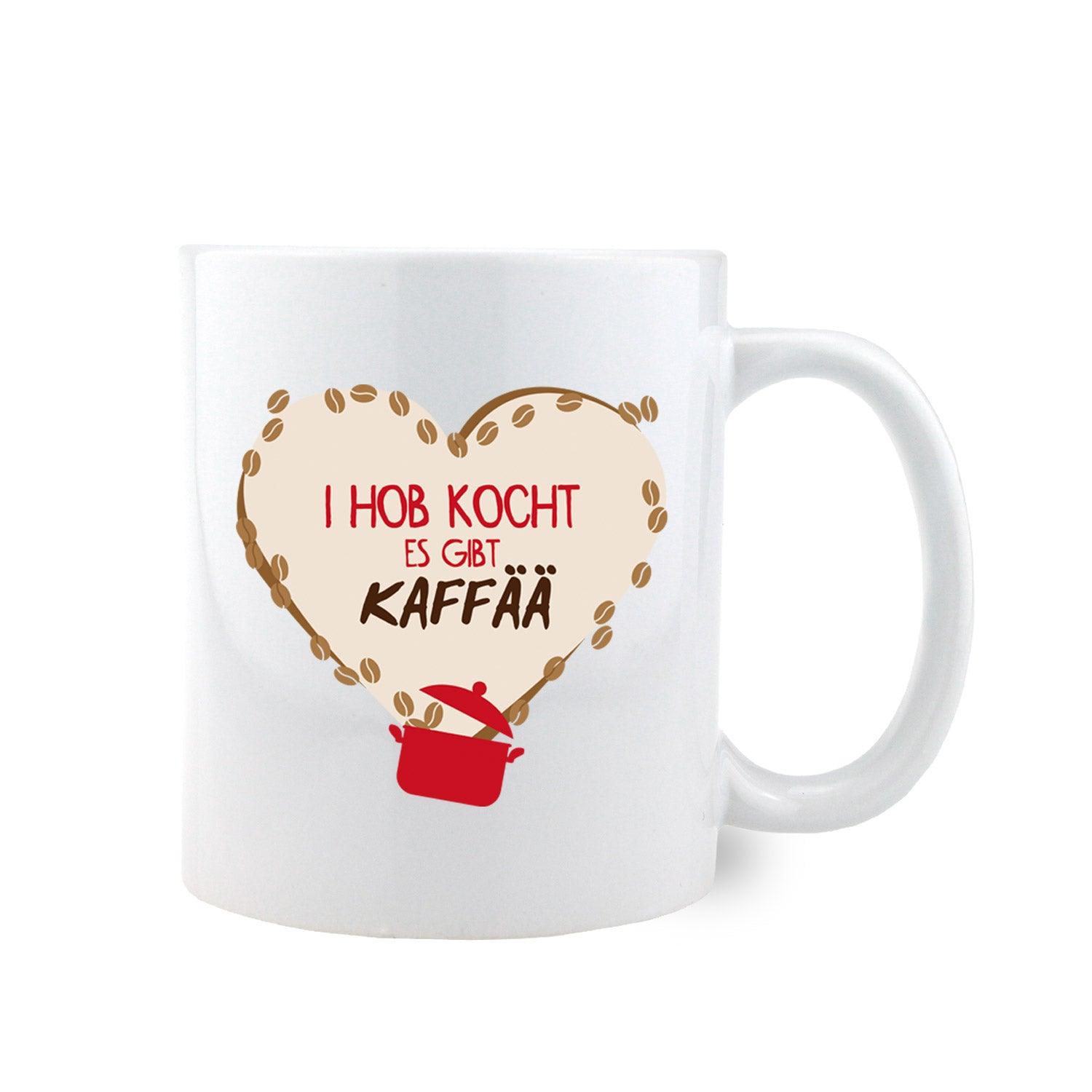 Weißes Kaffee-Haferl "I hob kocht, es gibt Kaffää" mit bayerischem Spruch, Herzform und Kaffeebohnen.
