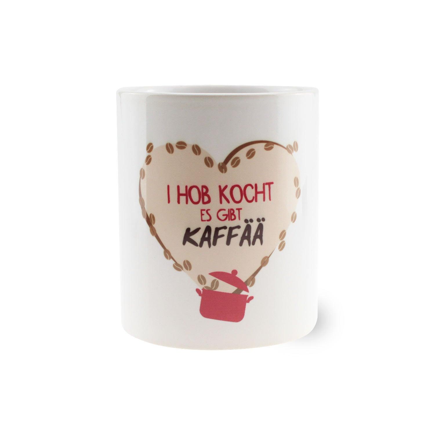 Weißes Kaffee-Haferl "I hob kocht, es gibt Kaffää" mit herzförmigem Kaffee-Bohnen-Design und Topf-Motiv.