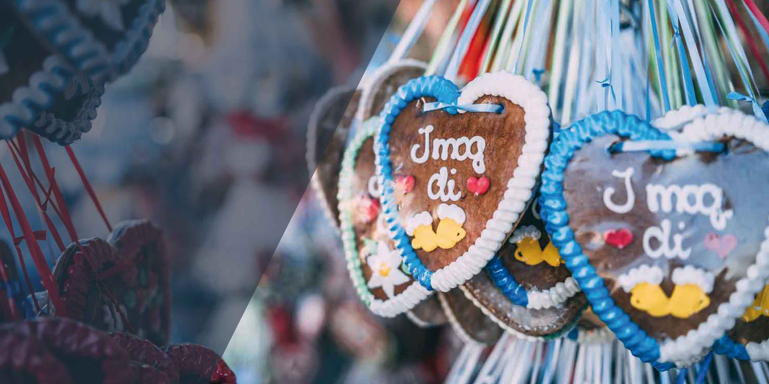 Bayerische Lebkuchenherzen mit der Aufschrift "I mog di", bunten Verzierungen und Bierkrügen.