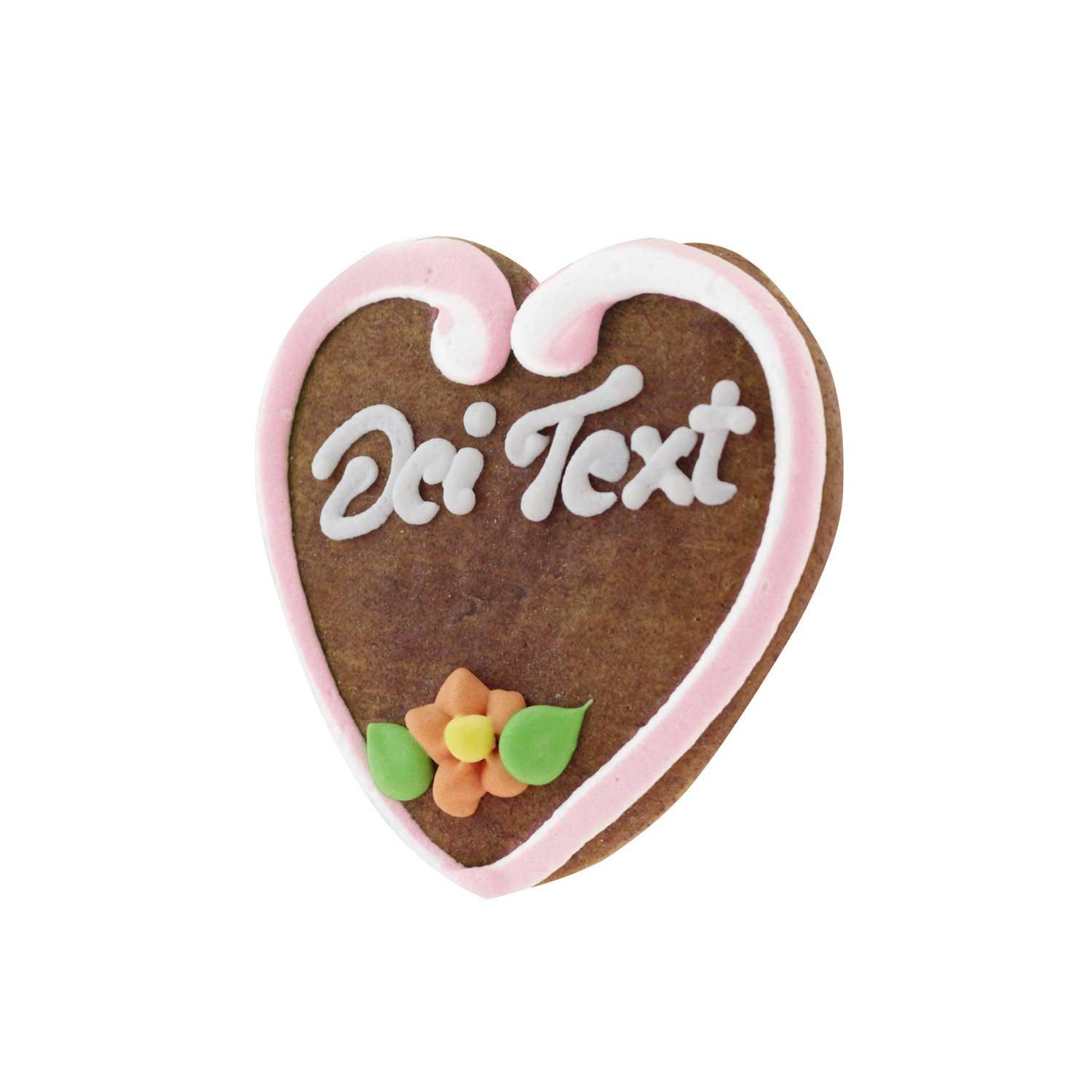 Lebkuchenherz mit rosafarbenem Zuckerrand, weißer Schrift "Dei Text" und orange-gelber Zuckerblume mit grünen Blättern.
