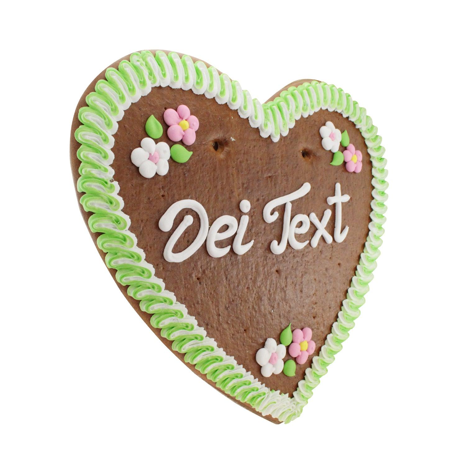 Lebkuchenherz mit individuell gestaltbarem Text "Dei Text", grüner und weißer Zuckerguss-Randverzierung, Blumenapplikationen.