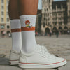 Weißer ®Pumuckl Tennissocken mit orangefarbenem Streifen und Eder-Figur, kombiniert mit weißen Sneakern.