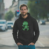 Mann trägt schwarzen ®Pumuckl Hoodie "Ampel-Edition" mit grünem Motiv im urbanen Umfeld