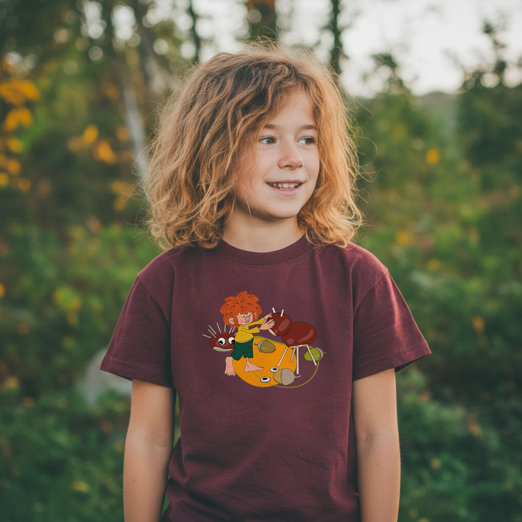 Kind mit Pumuckl Kinder T-Shirt Natur narrisch, der auf einem Kastanientier tanzt, im Grünen.