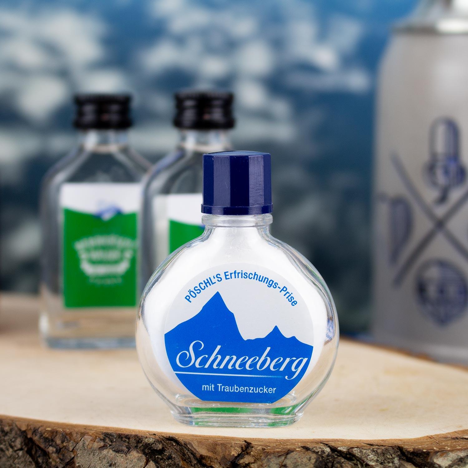 Transparente Glasflasche Pöschl's Schneeberg Schnupftabak mit blauem Logo und Traubenzucker auf Holzbrett.