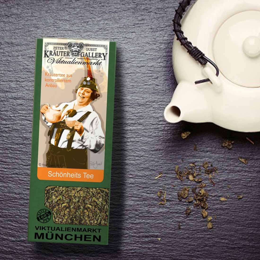 Grüne Teepackung vom Viktualienmarkt München mit „Schönheits Tee“ und einer weißen Teekanne auf dunklem Untergrund.