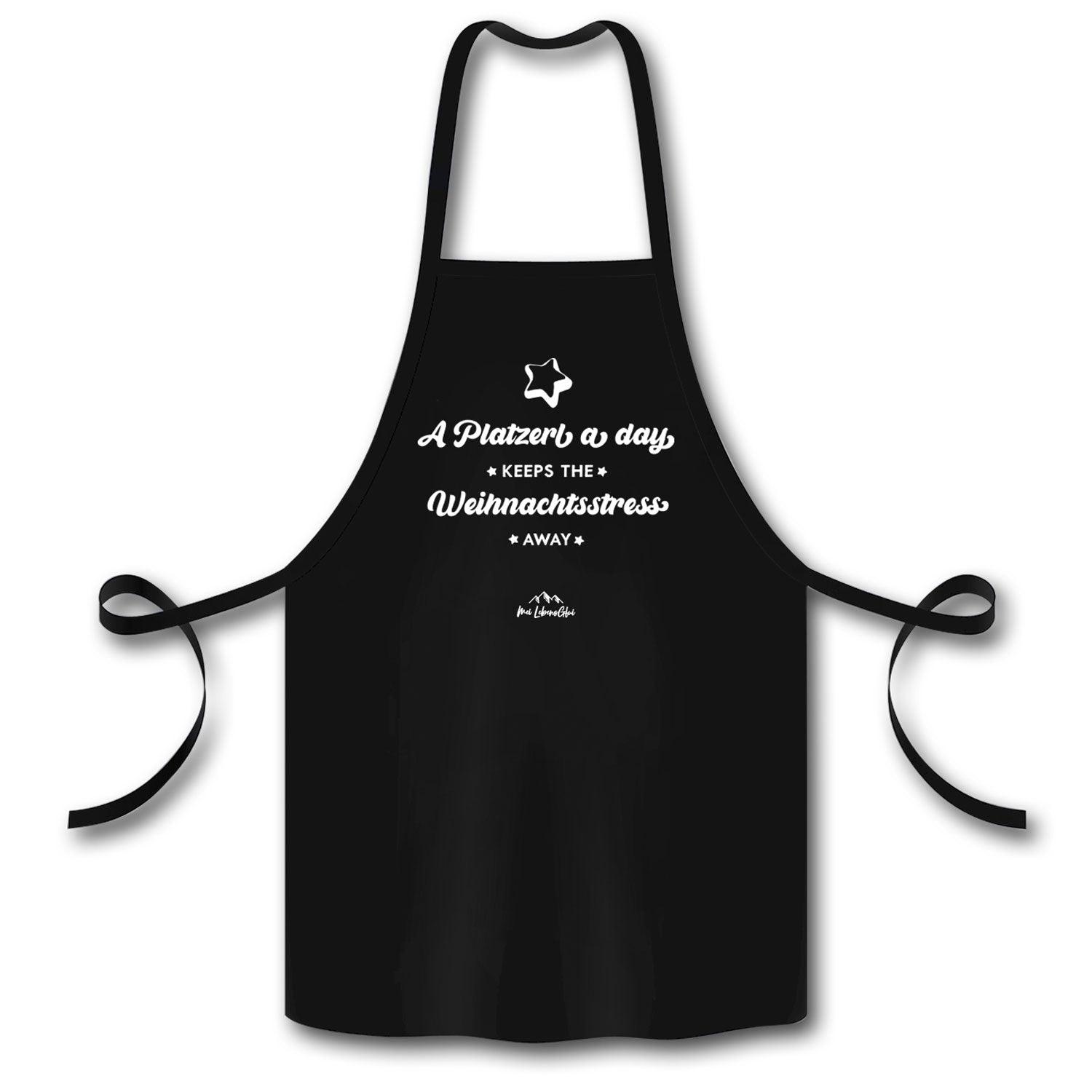 Schwarze Schürze "A Platzerl a day" mit weißem Weihnachtsmotiv und lustigem Spruch gegen Stress beim Backen.