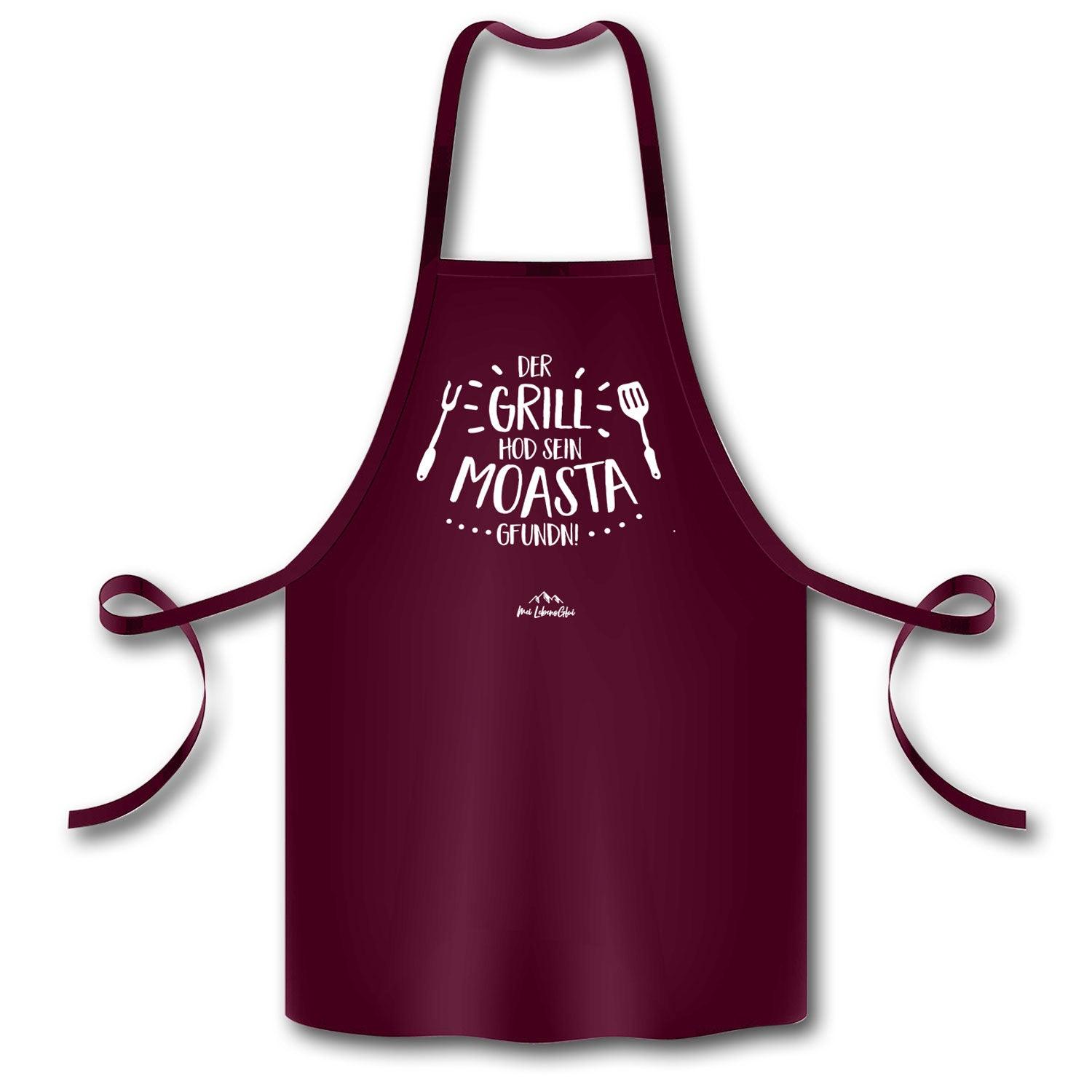 Bordeauxrote Grillschürze Grillmoasta mit weißem Schriftzug Der Grill hod sein Moasta gfundn und Grillbesteck-Motiv.
