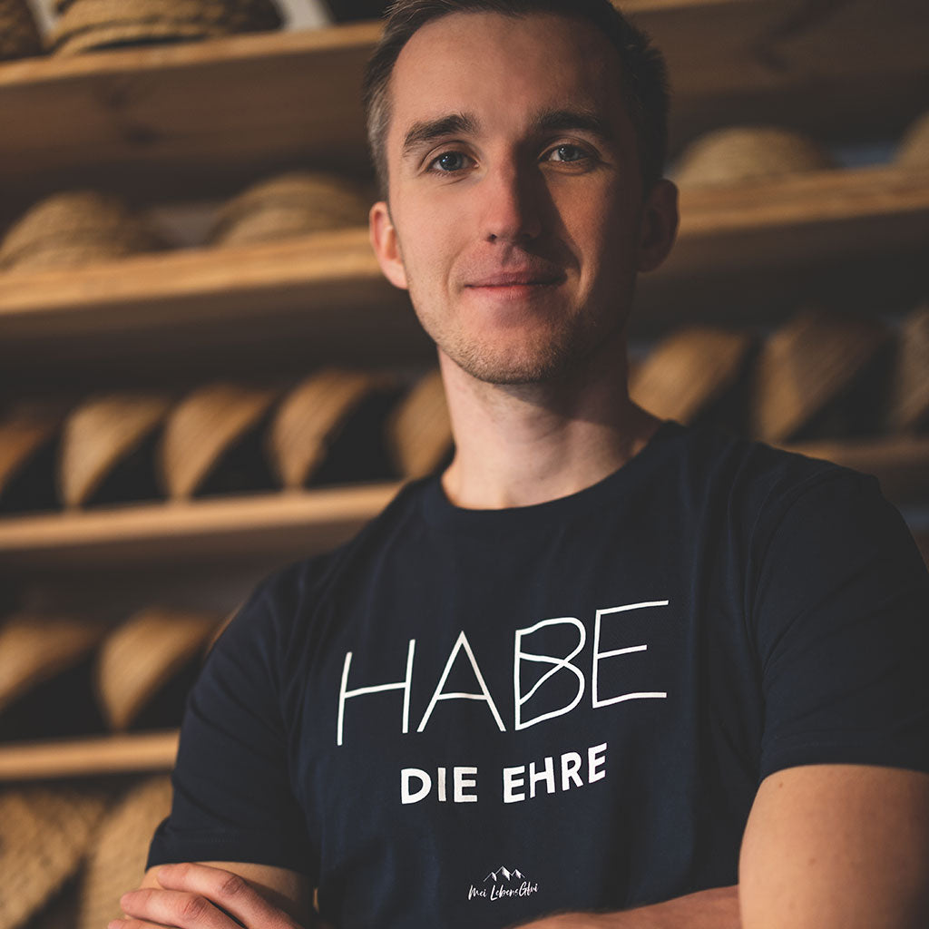 Junger Mann trägt dunkelblaues Herren T-Shirt Habe die Ehre in einer Holzhintergrund-Kulisse.