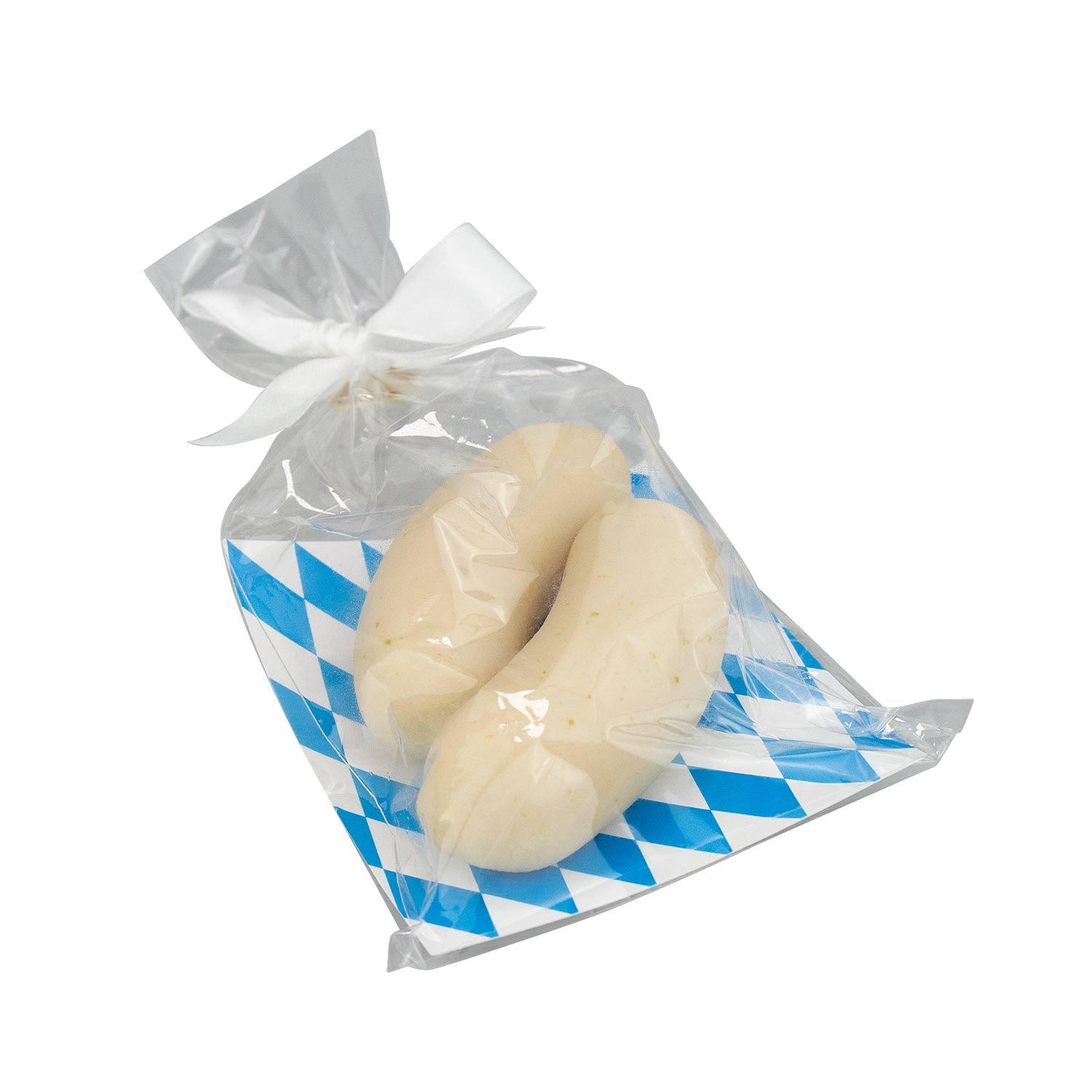 Zwei Weißwürste aus Marzipan verpackt in Klarsichttüte mit weiß-blauem Rautenmuster und Schleife.